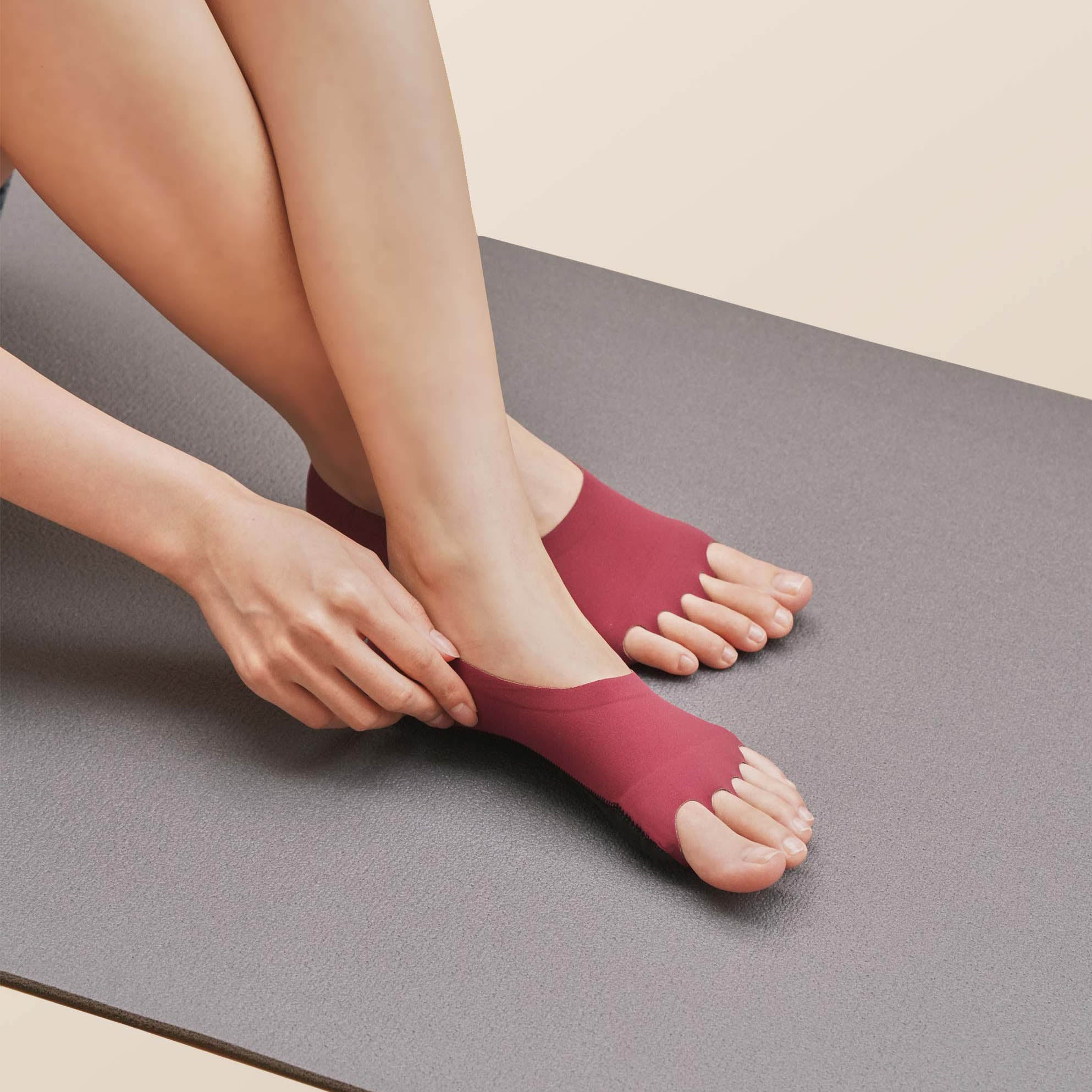 Woman on yoga mat wearing ONDO Yoga/Pilates socks in Maroon Red, depicting how the socks do not slip off feet