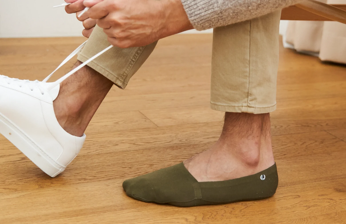 The Organic Cotton No Show Socks in Olive Green on foot paired with white sneakers
